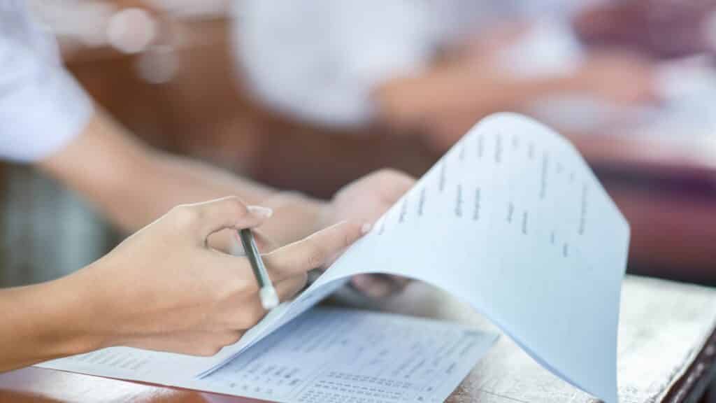 Deux mains blanches d'une femme avec un crayon dans la main droite tiennent et pointe du doigt une feuille d'évaluation de formation.