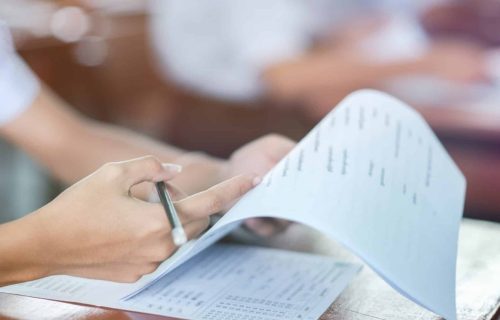 Deux mains blanches d'une femme avec un crayon dans la main droite tiennent et pointe du doigt une feuille d'évaluation de formation.
